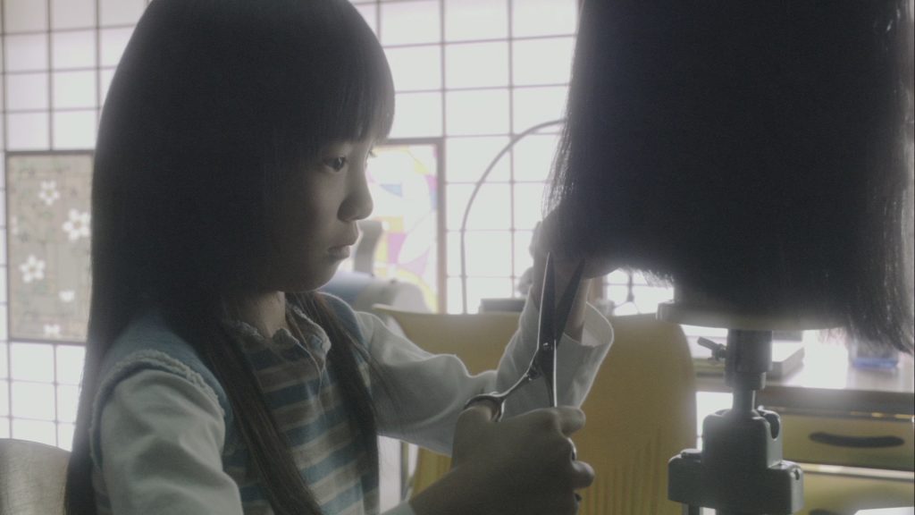 Mami, la nièce de Yûki, s'exerce à l'art de la coiffure.