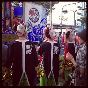 Trois personnes portent le masque du kitsune dans un matsuri