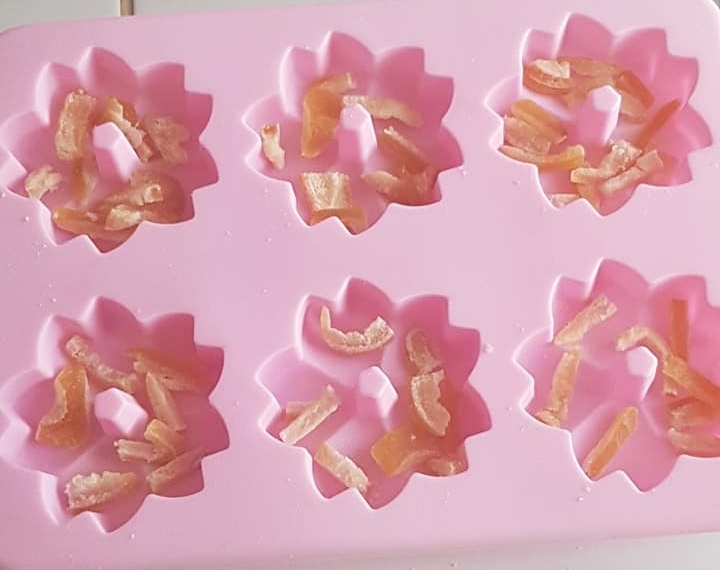 Mettre au fond du moule les zestes d'agrume