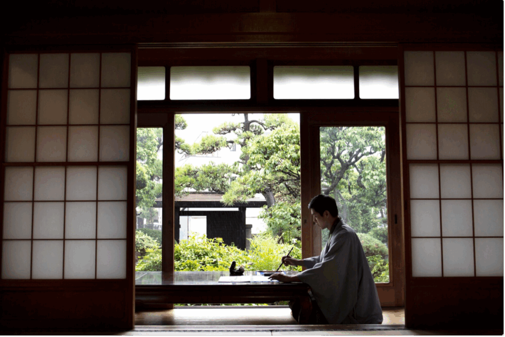 Homme japonais faisant de la calligraphie dans une pièce traditionnelle en tatami