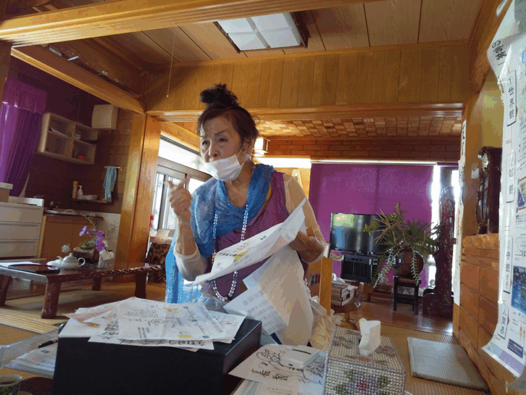 Une femme assise dans une grande pièce étudie des documents posés sur une table.