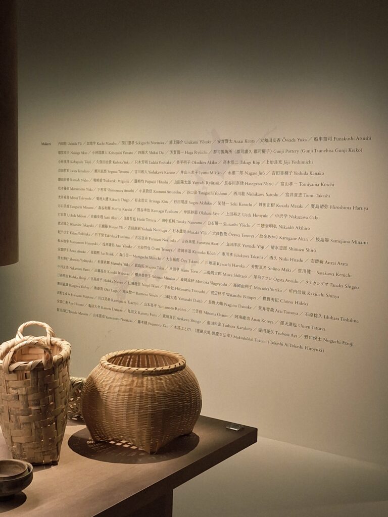 Vannerie en bambou de Yamasaki Daizô avec au fond le mur présentant les 123 créateurs présents dans l'exposition