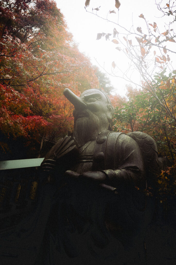 Statue au temple Daisho-in entourée d'érables dans la brume
