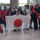Un groupe d'une vingtaine de personnes portent deux grands drapeaux français et japonais.